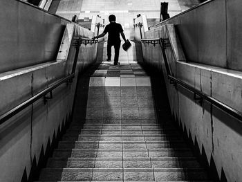 Rear view of man walking on staircase