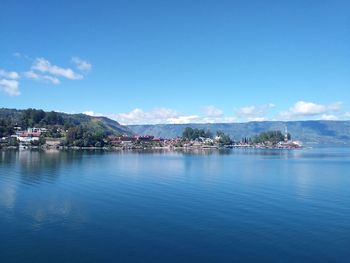 Scenic view of sea by buildings against blue sky