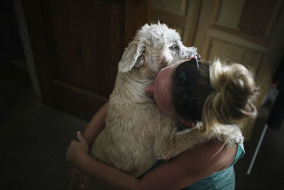 High angle view of woman embracing dog at home