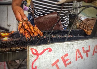 Close-up of man preparing food on barbecue grill