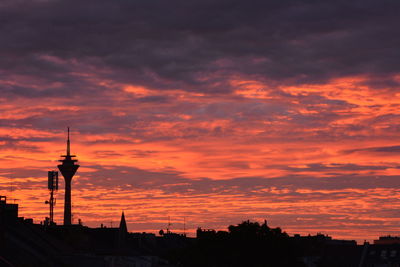 Silhouette buildings against cloudy sky during sunset
