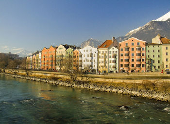 River by buildings against blue sky