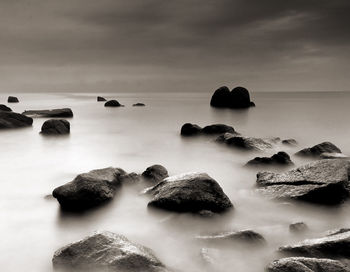 Rocks in calm sea against the sky