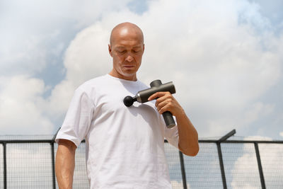 Young man using mobile phone against sky