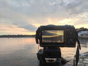 View of camera on sea against sky during sunset