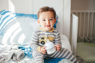 Portrait of cute baby boy on bed at home