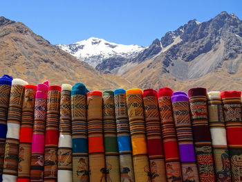 Stack of colorful fabrics for sale at market against mountains