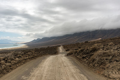 Road leading towards mountains against sky