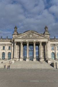 Facade of old building against cloudy sky