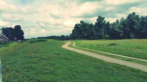 Scenic view of grassy field against cloudy sky