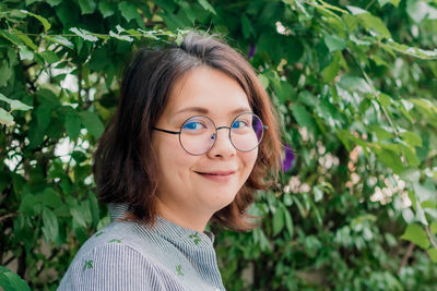 Portrait of young woman standing against plants