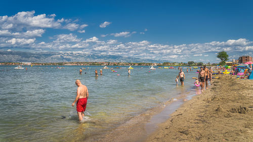 People enjoying at beach against sky