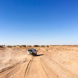 Motorcycle on road amidst desert against clear sky