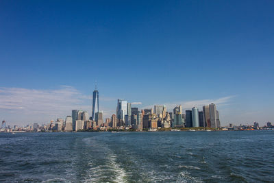 City at waterfront against blue sky