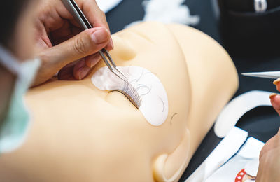 Cropped hand of beautician making false eyelash on mannequin