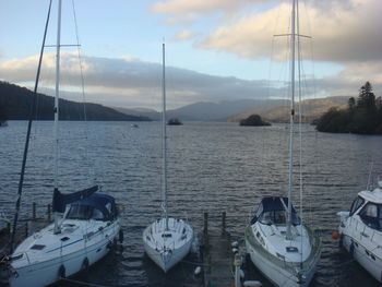 Sailboats moored in sea against sky