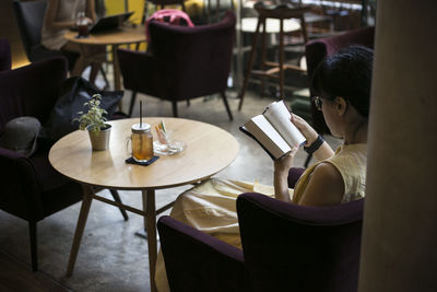 Woman reading book while sitting in cafe