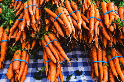 Farm fresh produce on tabletop at local farmer's market orange carrots in bundles with blue bands