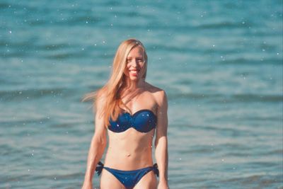 Beautiful young woman in bikini standing in sea