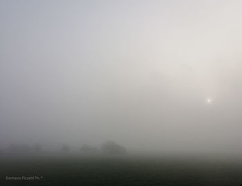 Scenic view of foggy field against sky at morning