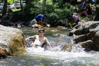 Portrait of shirtless man sitting in river