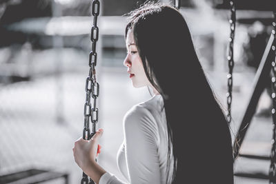 Side view of woman holding swing chain 