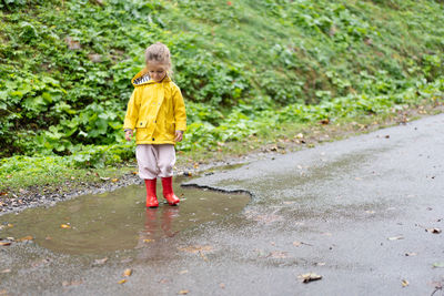 Rear view of girl walking on wet road