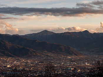 Aerial view of townscape and mountains against sky