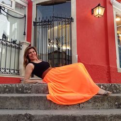 Portrait of smiling woman sitting on steps of building