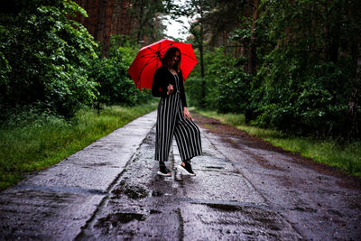 Rear view of woman standing on footpath during rainy season