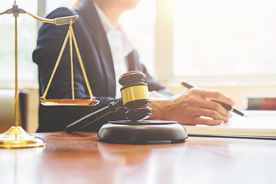 Close-up of gavel on table with female lawyer in background at office