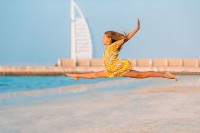 Girl jumping at beach against clear sky