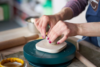 Midsection of woman making clay product in pottery workshop