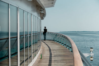 Rear view of man standing on cruise ship sailing in sea