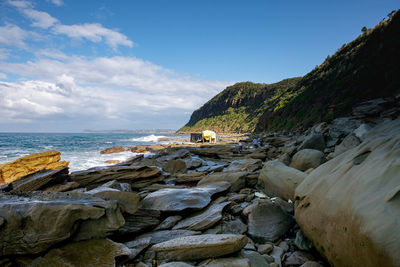 Rock formation on beach against sky