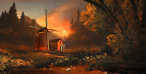 House and traditional windmill against sky during sunset