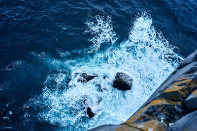 High angle view of waves splashing on rocks