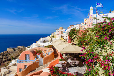 Buildings by sea against blue sky