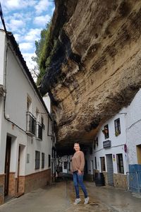 Full length of woman standing amidst residential buildings below mountain