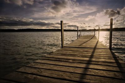 Pier over lake against sky during sunset