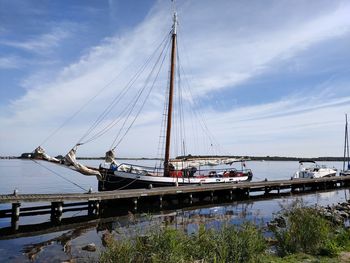 Sailboats moored on river against sky