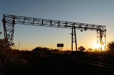 Silhouette of railroad tracks against clear sky during sunset