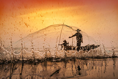 Reflection of silhouette man in sea against sky