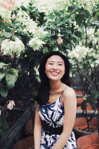 Portrait of a smiling young woman standing against plants