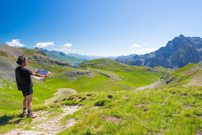 Rear view of woman standing on mountain against sky