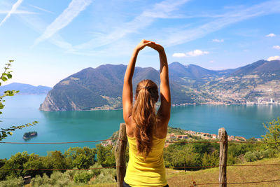 Rear view of woman looking at lake by mountains