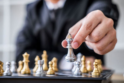 Midsection of businessman playing chess at desk