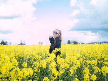 Smiling young woman standing on oilseed rape field