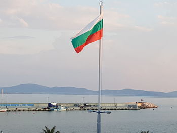 Flag by sea against sky