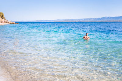 Man surfing in sea against clear sky